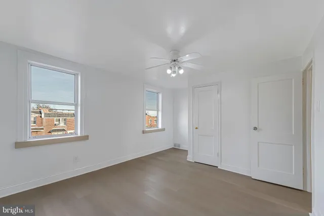 an empty room with windows and fan