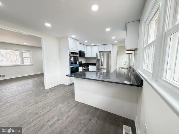 a kitchen with stainless steel appliances granite countertop a sink a stove and a microwave with wooden floor