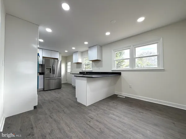 a view of a kitchen with granite countertop stainless steel appliances refrigerator sink and cabinets