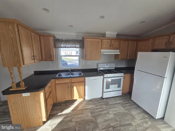 a kitchen with granite countertop a refrigerator stove top oven and sink