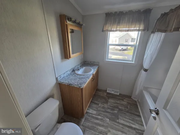 a bathroom with a granite countertop toilet sink and mirror