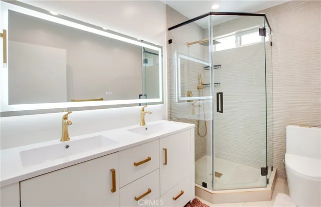 a bathroom with a shower sink vanity mirror and toilet