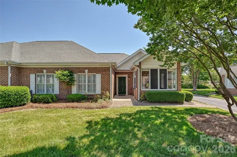 a view of a brick house with a big yard and large trees