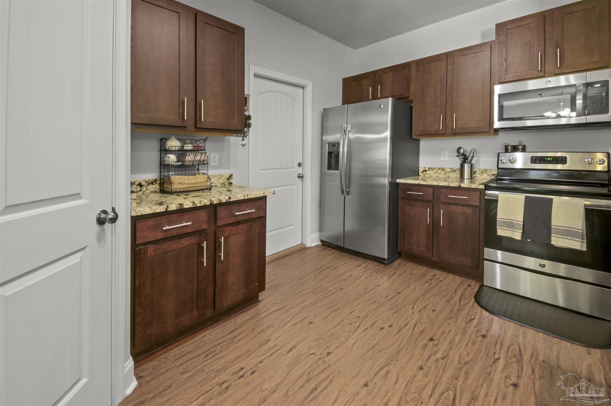 300 Cassady Lane Crestview, FL 32539 - Photo 9 of 25 a kitchen with stainless steel appliances granite countertop a stove top oven a refrigerator and a cabinets with wooden floors