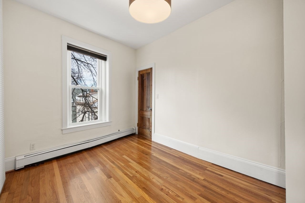 96 Brook Street, Unit 3 Brookline, MA 02445 - Photo 13 of 32 an empty room with wooden floor and windows