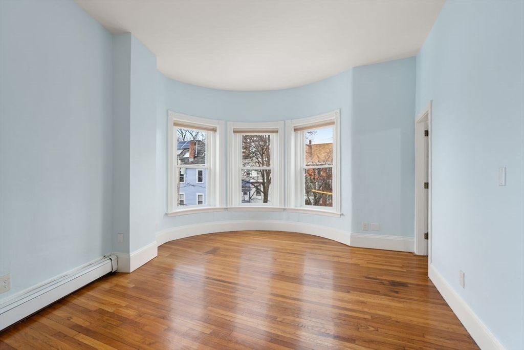 96 Brook Street, Unit 3 Brookline, MA 02445 - Photo 6 of 32 a view of an empty room with wooden floor and a window