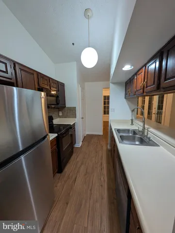 a kitchen with refrigerator a stove and wooden floor