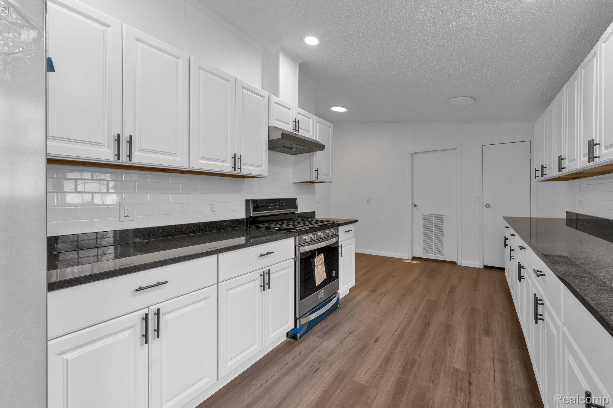 36085 Wick Road Romulus, MI 48174 - Photo 29 of 43 Kitchen featuring gas stove, white cabinetry, dark stone counters, dark wood-style floors, and decorative backsplash