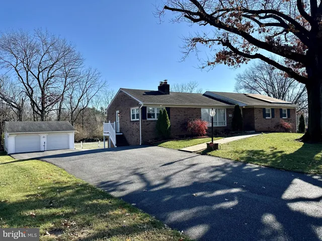 a front view of house with yard and trees in the background