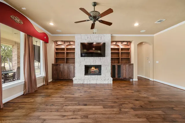 a view of a livingroom with a fireplace a ceiling fan and windows