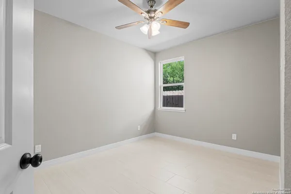 an empty room with a window and a ceiling fan