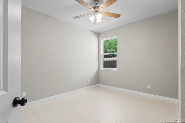 an empty room with a window and a ceiling fan