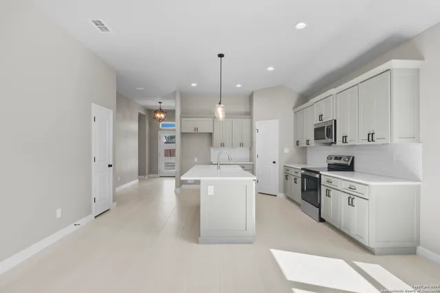a large white kitchen with white cabinets and stainless steel appliances