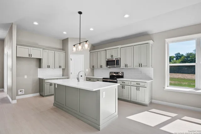 a kitchen with stainless steel appliances granite countertop a stove top oven a sink a refrigerator a center island and cabinets