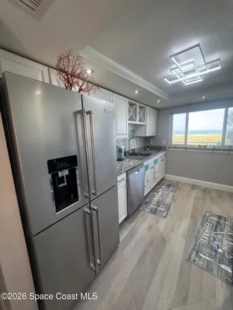 a kitchen with granite countertop a refrigerator a sink a stove and cabinets
