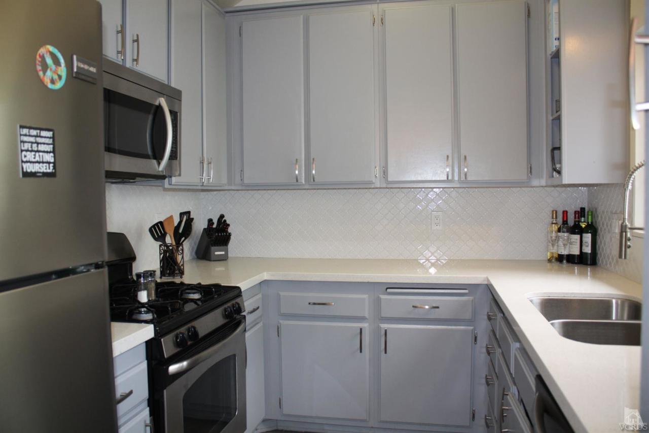 661 Arneill Road Camarillo, CA 93010 - Photo 6 of 22 a kitchen with white cabinets and black appliances