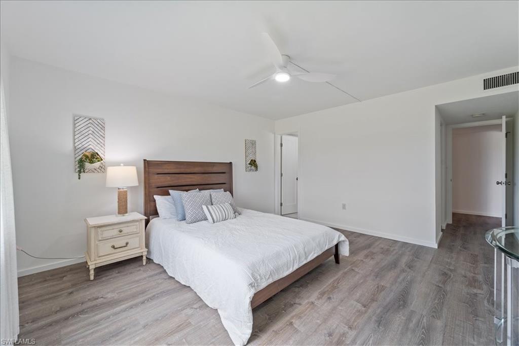 307 Goodlette-Frank Road, Unit B202 Naples, FL 34102 - Photo 22 of 32 a bedroom with a bed and a night stand