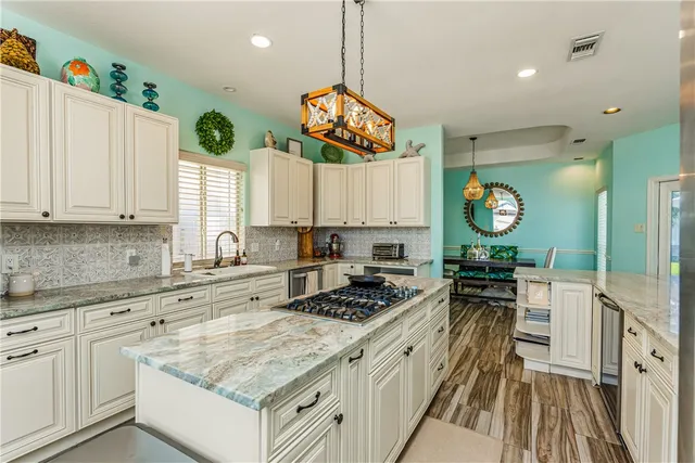 a kitchen with granite countertop a stove a sink a refrigerator and a stove