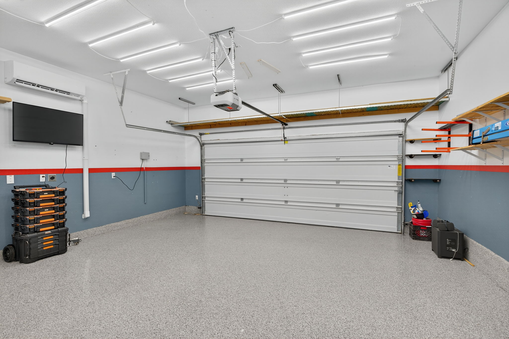 13300 Craven Lane Manor, TX 78653 - Photo 3 of 40 Hello Garage Enthusiasts! This home features a heated and cooled garage with a mini-split system, bright LED lighting, ceiling fan, and mounted TV for convenience. Fully epoxied flooring with ample shelving and wall racks to keep tools and storage organized.
