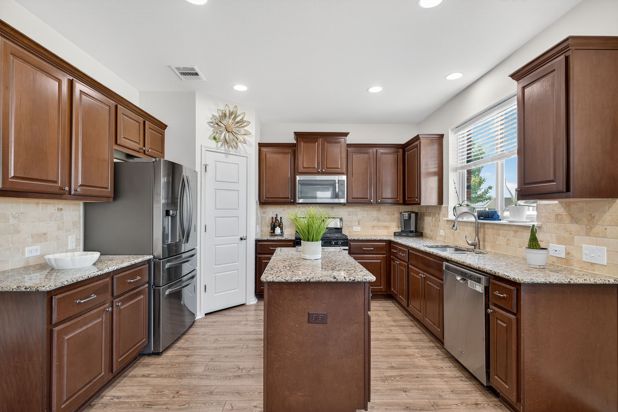 13300 Craven Lane Manor, TX 78653 - Photo 4 of 40 Kitchen featuring light stone granite counters, appliances with stainless steel finishes, backsplash, kitchen island, pull-out trash bin, generous pantry and recessed lighting. The fridge is also included with this home!