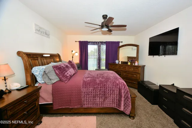 a bedroom with a bed dresser and a flat tv screen