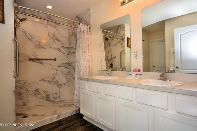 a bathroom with a double vanity sink mirror and shower