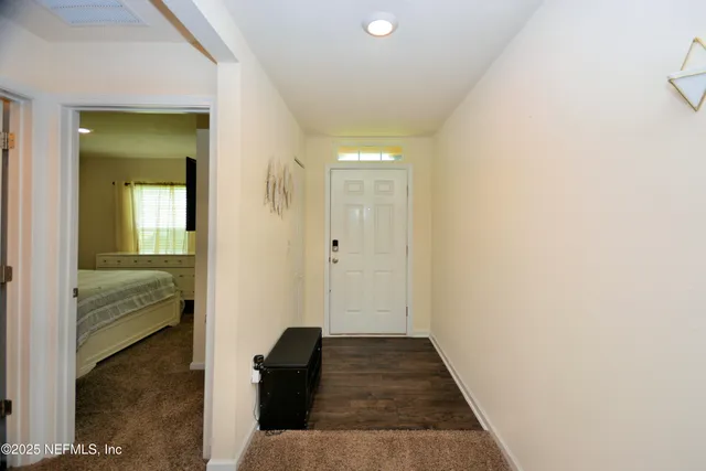 a view of a hallway with wooden floor and a bathroom