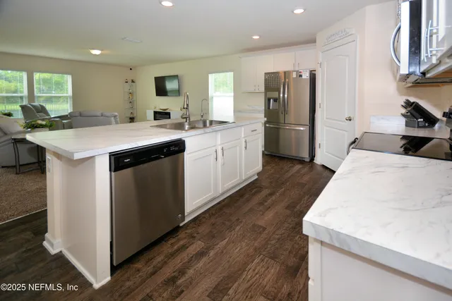 a kitchen with stainless steel appliances granite countertop a refrigerator a sink dishwasher a stove and a refrigerator