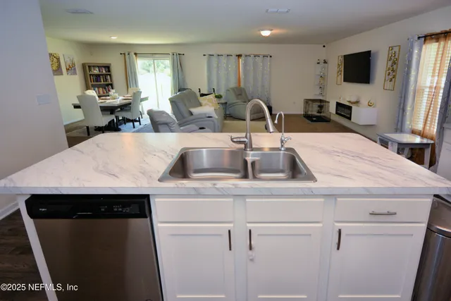 a kitchen with a sink a refrigerator and chairs