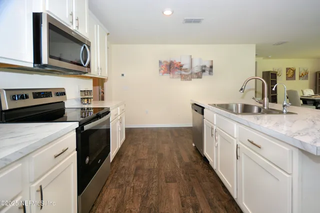 a kitchen with granite countertop cabinets stainless steel appliances and wooden floor