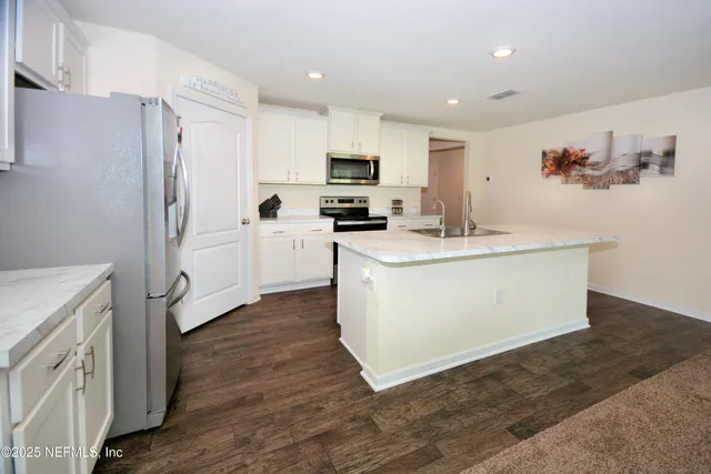 a kitchen with a sink wooden floor and stainless steel appliances
