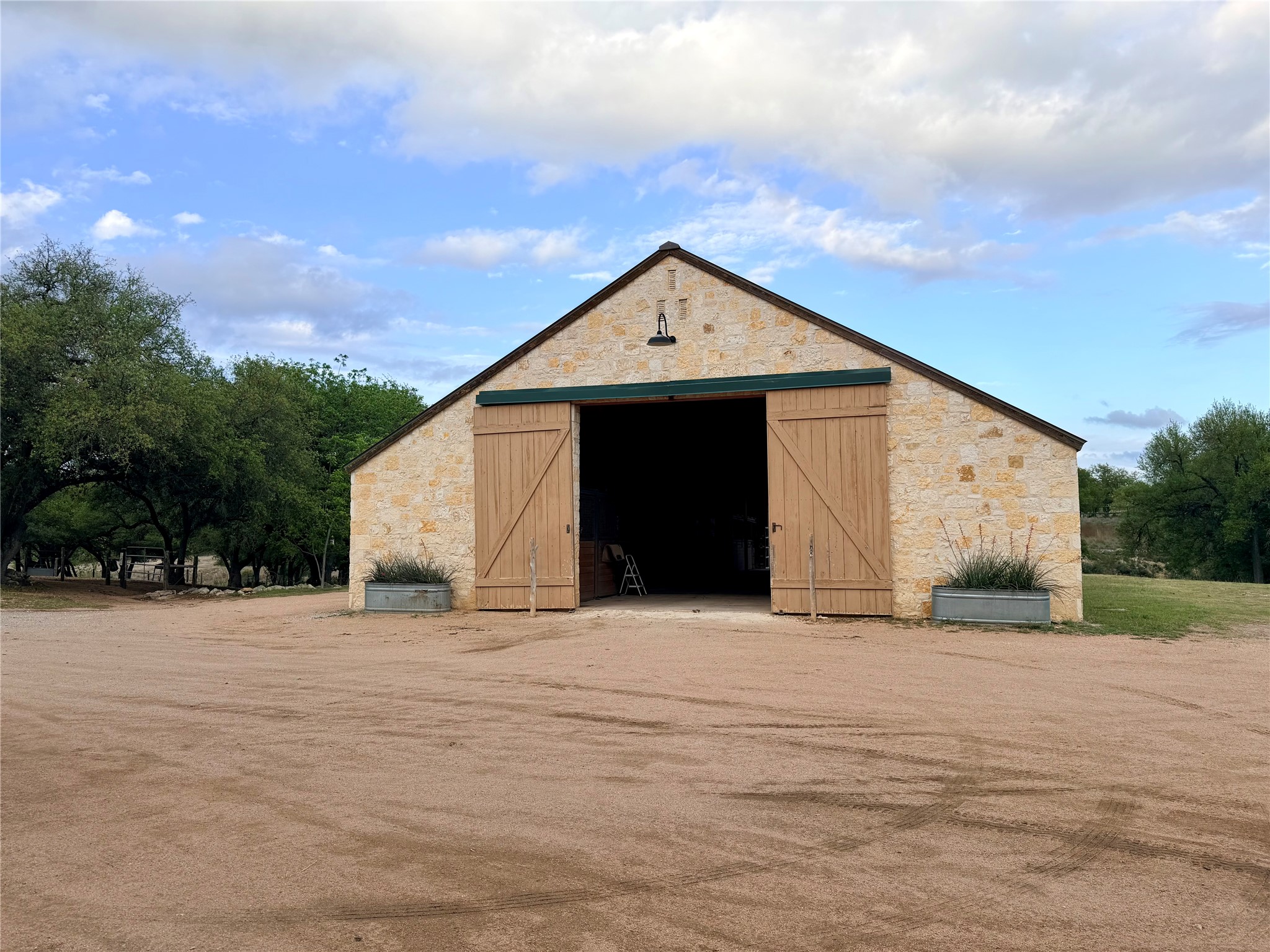768 North Walnut Springs Road Johnson City, TX 78636 - Photo 20 of 22 The property features a stone-clad building with a pitched roof and large wooden sliding doors