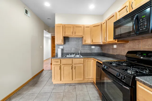 a kitchen with stainless steel appliances granite countertop a stove a sink and a microwave