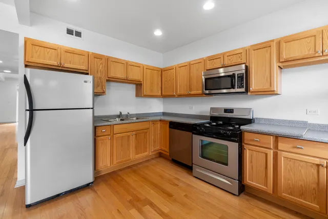 a kitchen with stainless steel appliances granite countertop a refrigerator stove a sink and a microwave