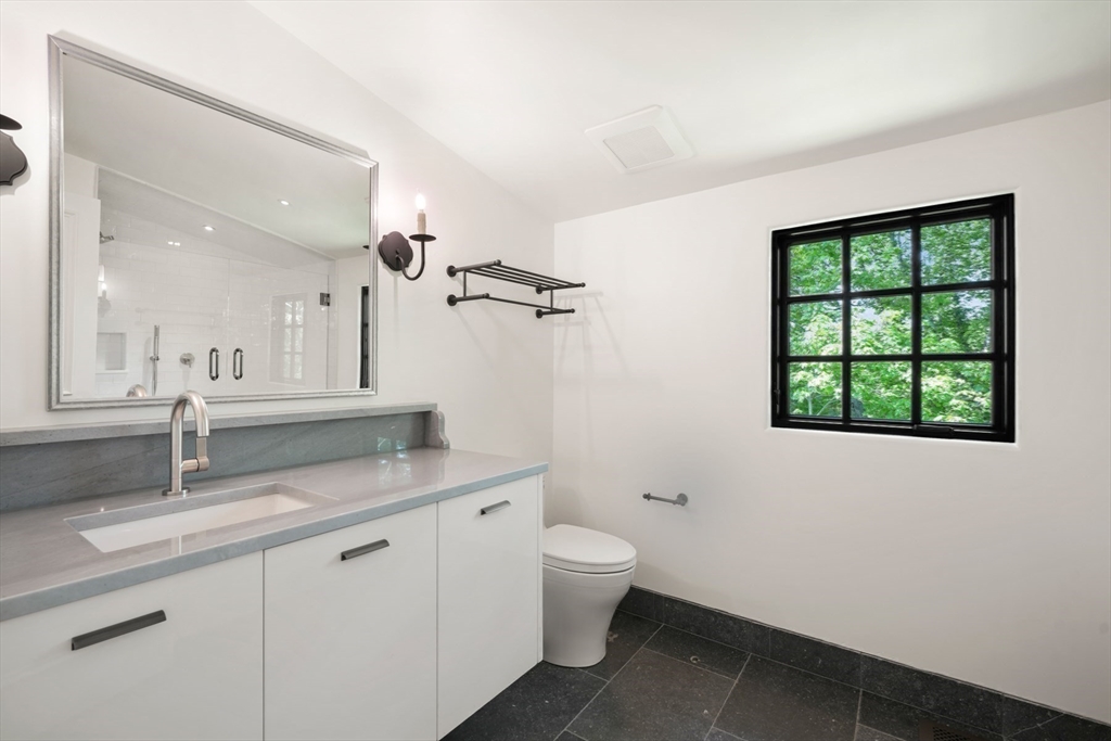 709 Boston Post Road Weston, MA 02493 - Photo 27 of 42 a bathroom with a granite countertop sink a toilet a mirror and a window