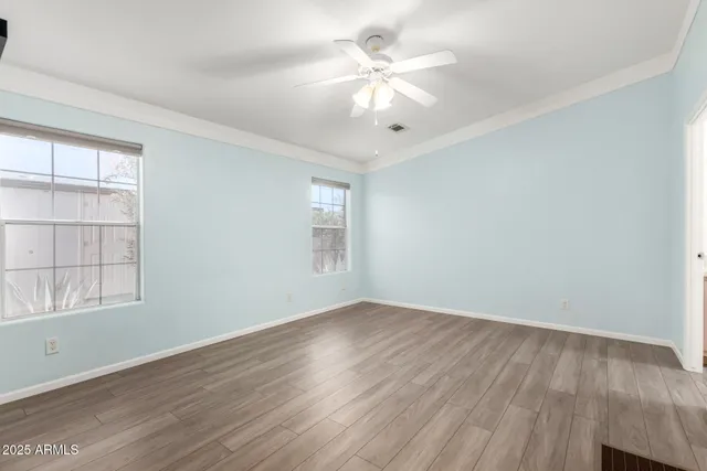 an empty room with wooden floor chandelier fan and windows