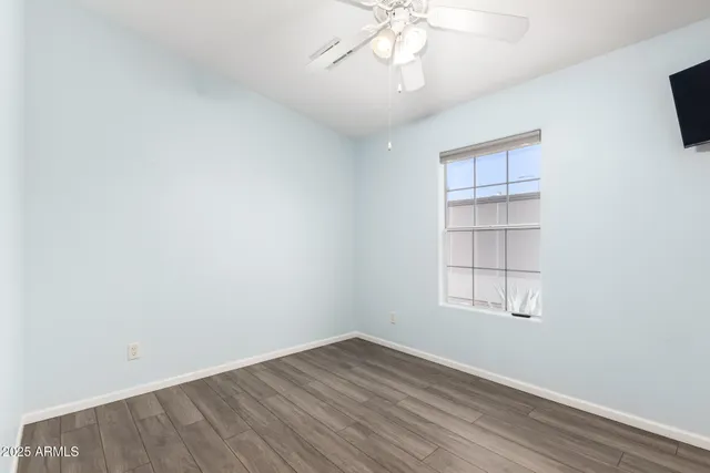 an empty room with wooden floor chandelier fan and windows