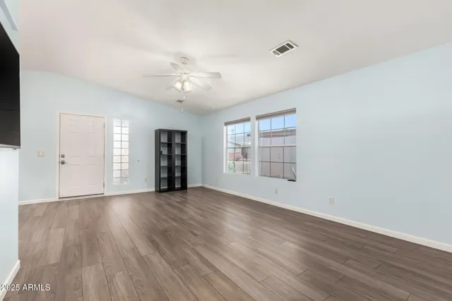 an empty room with wooden floor and windows