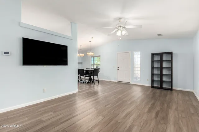 a view of a livingroom with a flat screen tv wooden floor and a ceiling fan
