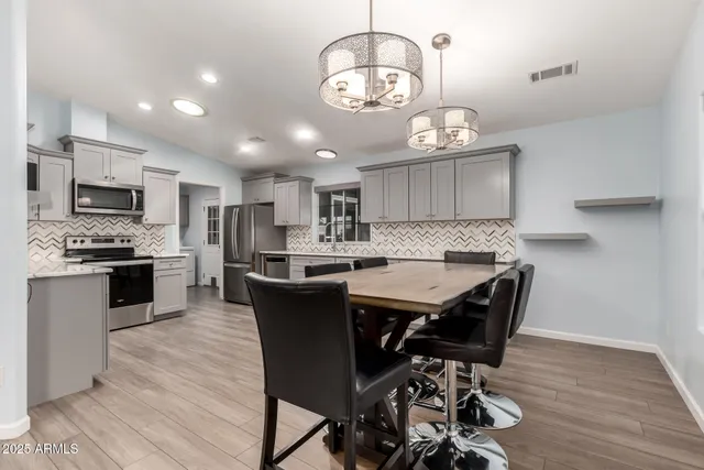 a kitchen with a dining table chairs stainless steel appliances and cabinets