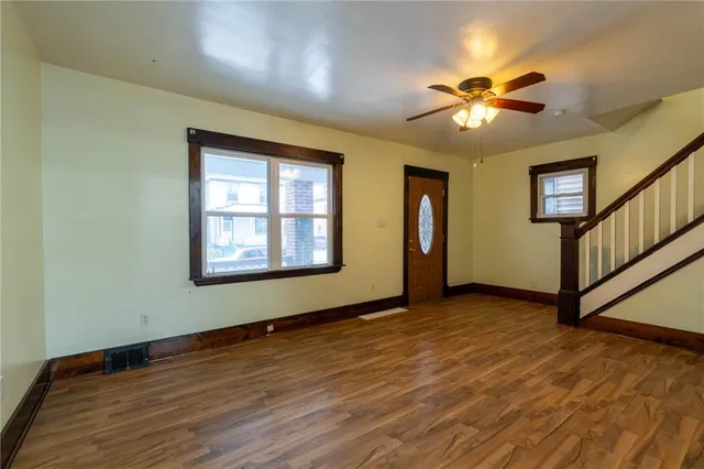 a view of an empty room with window and wooden floor