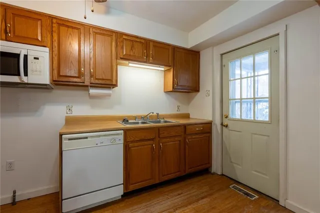 a kitchen with stainless steel appliances granite countertop a sink and cabinets with wooden floor