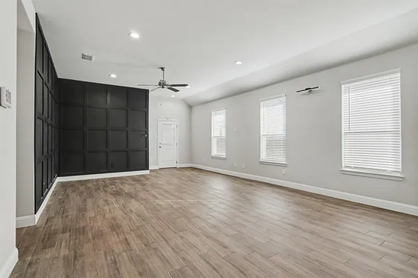 a view of an empty room with wooden floor and windows