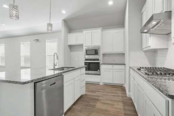 a kitchen with stainless steel appliances granite countertop a kitchen island hardwood floor sink and stove