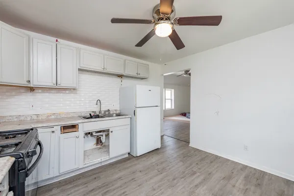 a kitchen with granite countertop a refrigerator a sink a stove and white cabinets