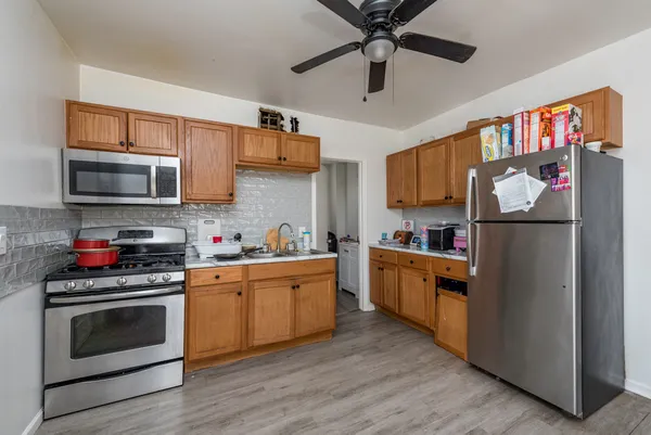 a kitchen with stainless steel appliances granite countertop a refrigerator a stove top oven a sink and dishwasher with wooden floor
