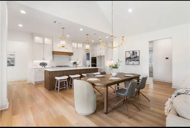 a dining hall with stainless steel appliances kitchen island granite countertop a table chairs and a refrigerator