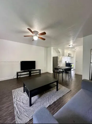 a living room with furniture and a flat screen tv with kitchen view