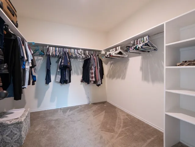 a view of walk in closet with clothes and shoes