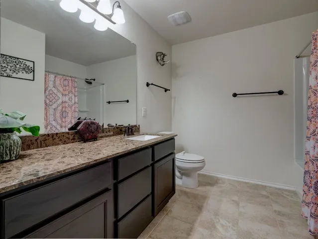 a bathroom with a granite countertop sink a toilet and a mirror